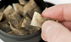 мужчина берёт пакетик снюса из коробки